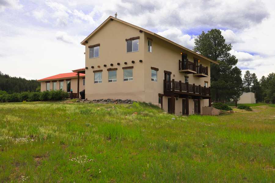 Corner view of the lodge with stacked log balconies and tall ponderosa pines