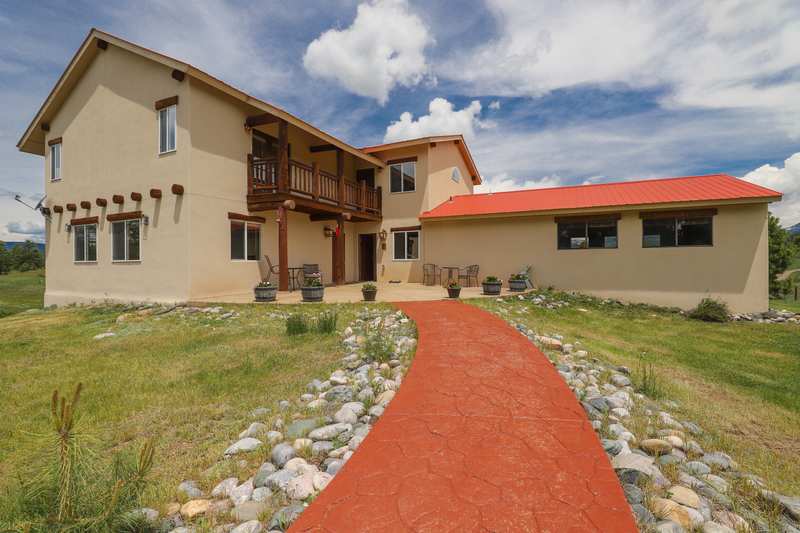 Curved red walkway leading to the front entry and log balcony of Piedra Pines Lodge