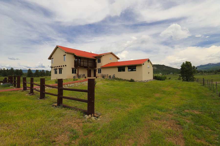 Front of the lodge with patio seating, flower barrels and the split-rail fence