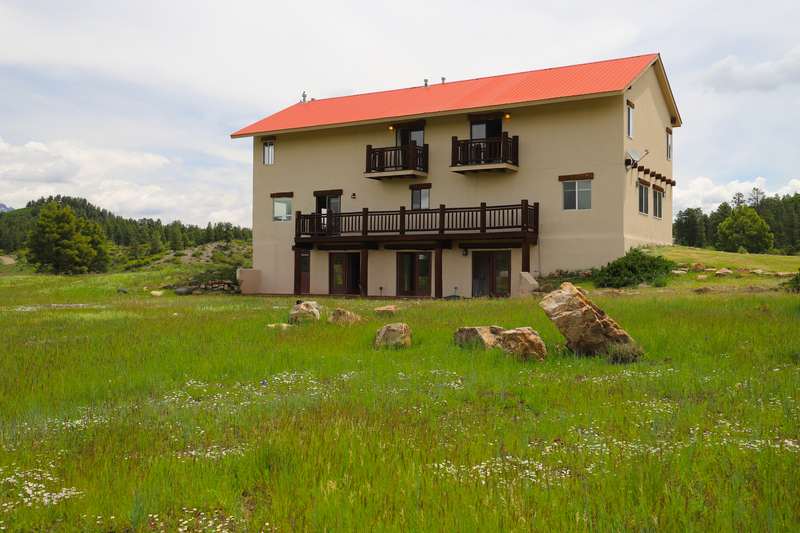 Back of the lodge across a wildflower meadow with sandstone boulders