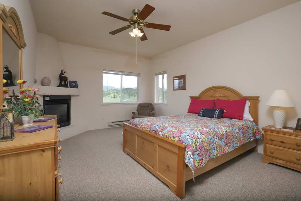 Upper-floor queen bedroom with a corner kiva fireplace and mountain views