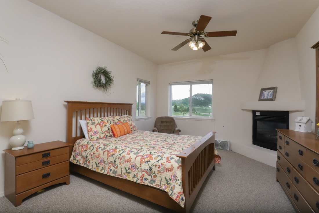 Upper-floor queen bedroom with a kiva fireplace and window onto the hill