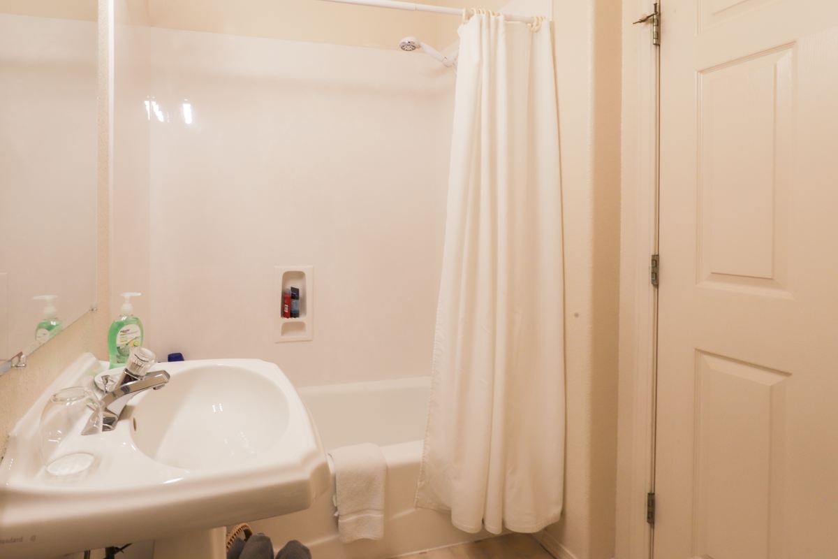 Private bathroom with pedestal sink and tub