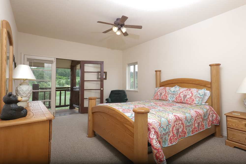 Upper-floor queen bedroom with French doors to a private balcony over the meadow