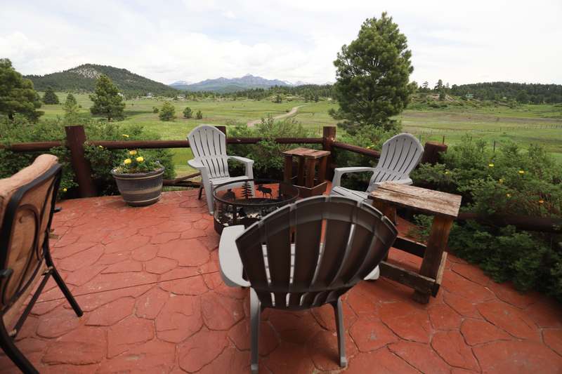Fire pit with Adirondack chairs on the back patio facing the San Juan Mountains