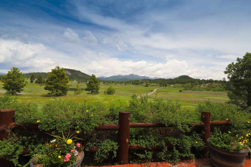 View from the back patio over the split-rail fence to the valley and San Juan peaks