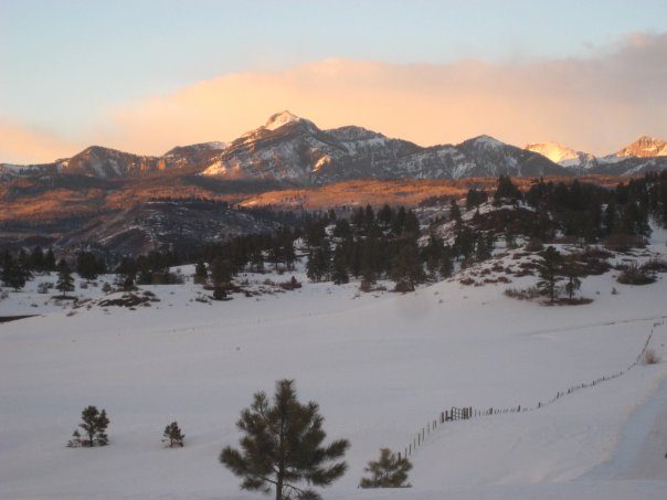 Snow-covered meadow below the San Juan Mountains glowing at sunset